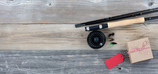Fathers day gift box and fishing items on rustic wooden plank background