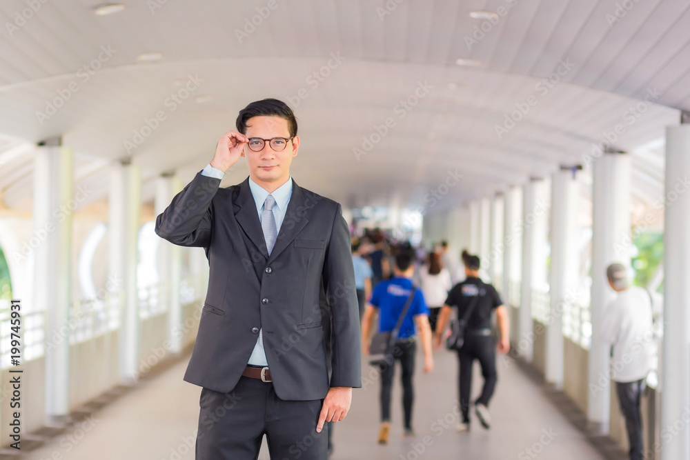 Young Asia handsome businessman with his glasses standing on walkway of modern city. Young Asia handsome businessman with his glasses standing on walkway of modern city.