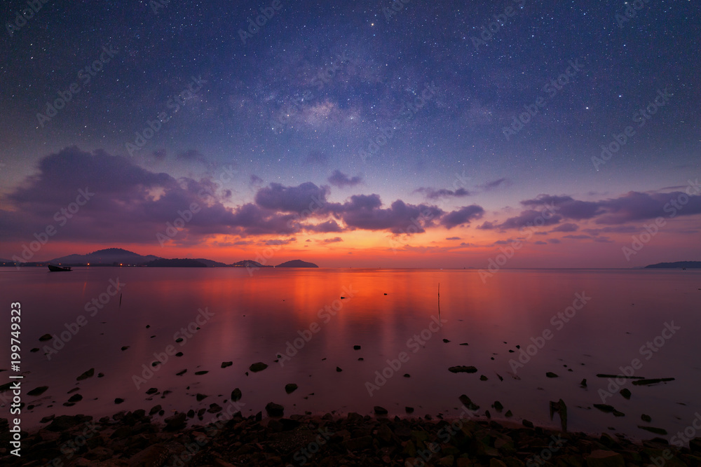 Long exposure image of dramatic sunset or sunrise,sky clouds over tropical sea and milky way galaxy.