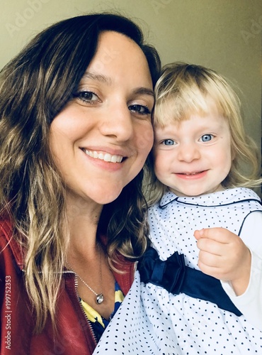 Selfie, young mother kissing her 2 years old toddler Blonde beautiful daughter