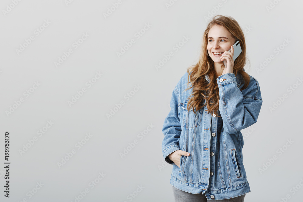 Looking from window and talking with boyfriend, dreaming to be near. Portrait of romantic attractive blonde woman in trendy denim jacket, looking left while talking on smartphone, arranging meeting Looking from window and talking with boyfriend, dreaming to be near. Portrait of romantic attractive blonde woman in trendy denim jacket, looking left while talking on smartphone, arranging meeting