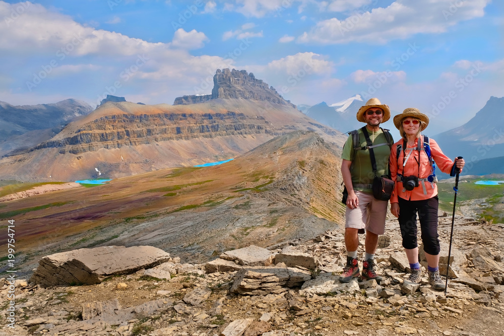 Happy family travelling in Canadian Rockies. Active man and woman hikers on trail. Dolomite Mountains in Banff National Park. Rocky Mountains. Alberta. Canada. Happy family travelling in Canadian Rockies. Active man and woman hikers on trail. Dolomite Mountains in Banff National Park. Rocky Mountains. Alberta. Canada.