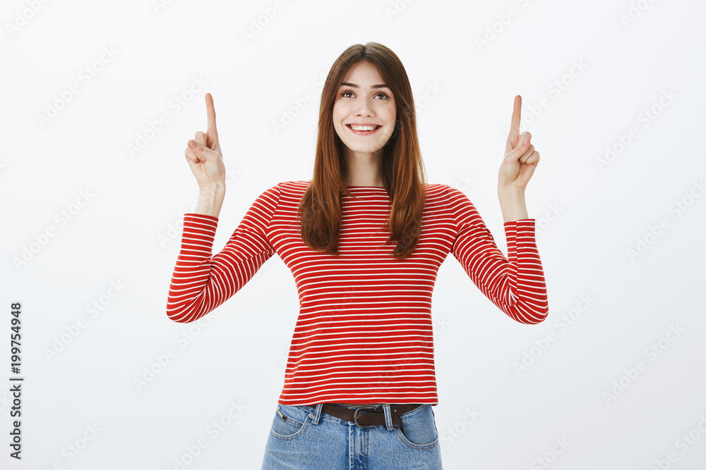 Girl amazed with beautiful rainbow. Indoor shot of pleased dreamy attractive woman in striped blouse, looking and pointing up, smiling broadly, being uplifted and happy over gray background Girl amazed with beautiful rainbow. Indoor shot of pleased dreamy attractive woman in striped blouse, looking and pointing up, smiling broadly, being uplifted and happy over gray background