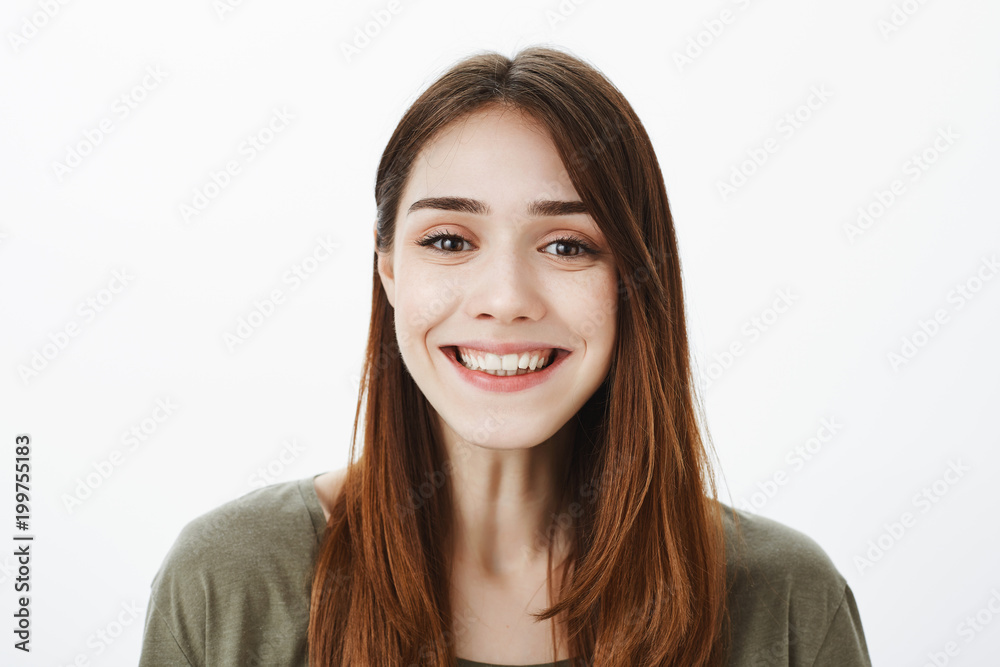 Close-up portrait of friendly charming european brunette with broad positive smile, standing over gray background, enjoying nice talk with friend and feeling relaxed and confident Close-up portrait of friendly charming european brunette with broad positive smile, standing over gray background, enjoying nice talk with friend and feeling relaxed and confident