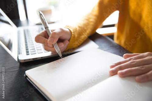 Tableau sur toile close up of business woman's hands using laptop and writing in notepad