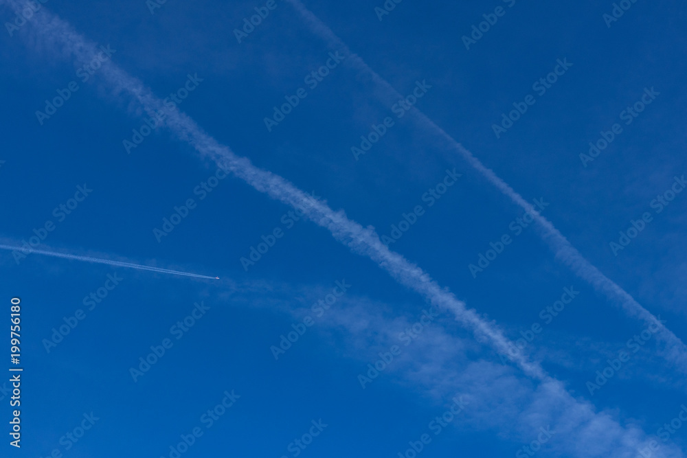 Contrails in blue sky with airplane flying Contrails in blue sky with airplane flying