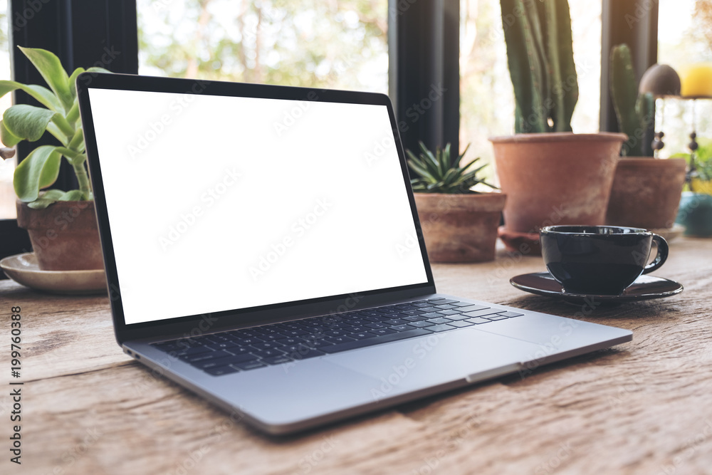 Top view mockup image of hands using and typing on laptop with blank white desktop screen on vintage wooden table in cafe