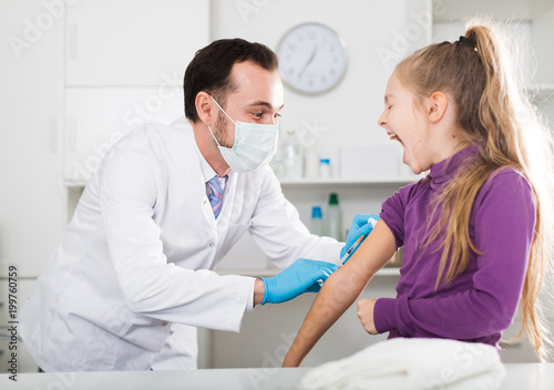 Male doctor injecting little patient