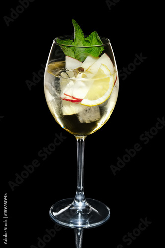 Apple cocktail with a sparkling wine with ice cubes in wine glass isolated on black