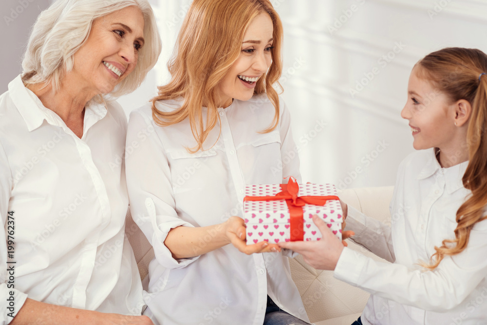 Happy birthday. Selective focus on tender women looking at a little girl with eye full of love while sitting next to her and congratulating her at home. Happy birthday. Selective focus on tender women looking at a little girl with eye full of love while sitting next to her and congratulating her at home.