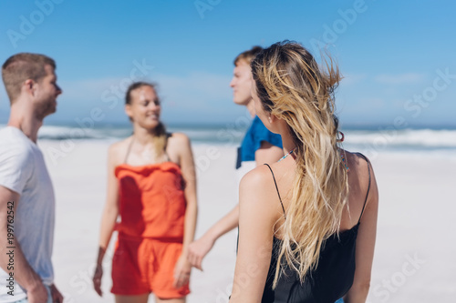Group of young friends chatting on a windy beach