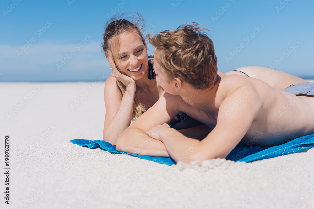 Fototapeta premium Young couple relaxing on a beach chatting