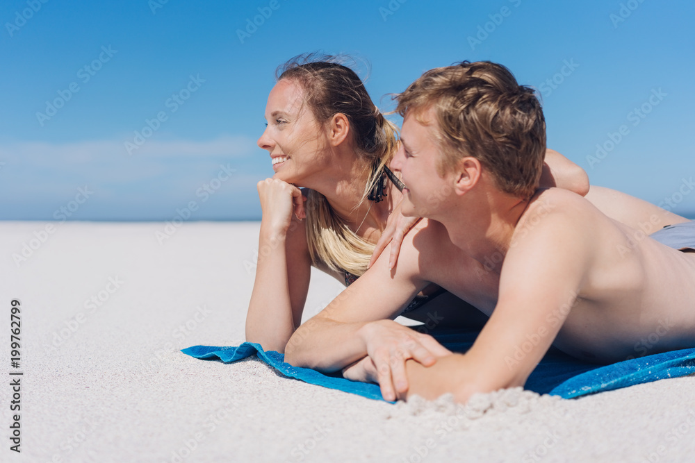 Happy young couple sunbathing on a sandy beach Happy young couple sunbathing on a sandy beach