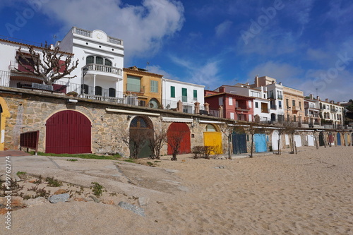 Colored wooden doors of boat storage on the beach and houses in the village of Calella de Palafrugell, Mediterranean, Spain, Costa Brava, Catalonia, Baix Emporda