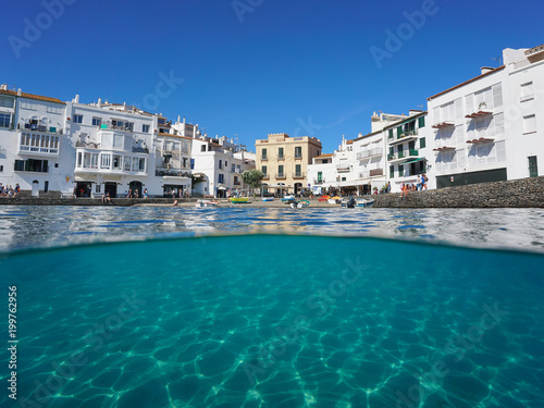 Fototapeta Naklejka Na Ścianę i Meble -  Waterfront village of Cadaques with a small beach and a sandy seabed underwater, split view above and below water surface, Mediterranean sea, Costa Brava, Spain