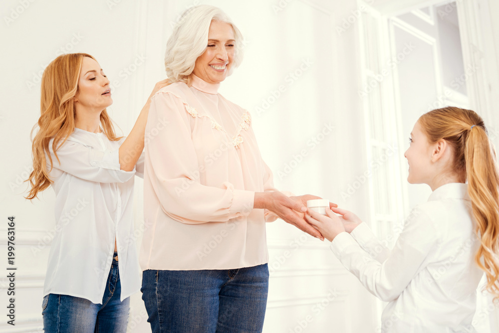 Obraz premium You are the prettiest granny. Tender nature daughter and thoughtful preteen granddaughter taking care of their beautiful grandmother and helping her with dressing up at home.