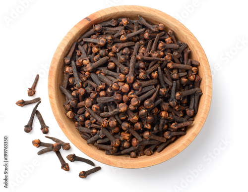 dried cloves in the wooden plate, isolated on white, top view photo