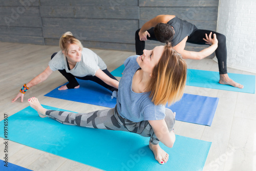 Healthy fitness, yoga and sport lifestyle concept. Group of people meditating in different poses at studio on exercise blue mat with trainer.