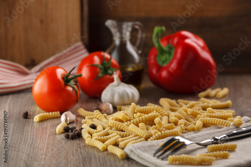 Italian raw pasta fusilli on the background of other ingredients for cooking