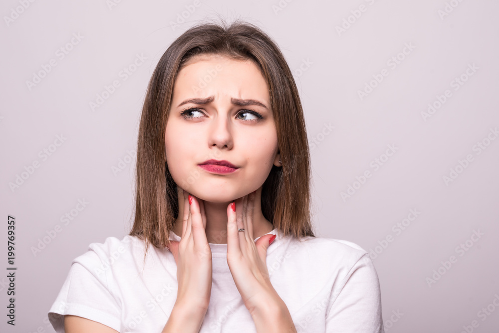 beautiful young woman has a sore throat, close-up, isolated on a gray background beautiful young woman has a sore throat, close-up, isolated on a gray background
