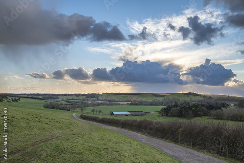 Beautiful stormy moody cloudy sky over English countryside landscape at dusk