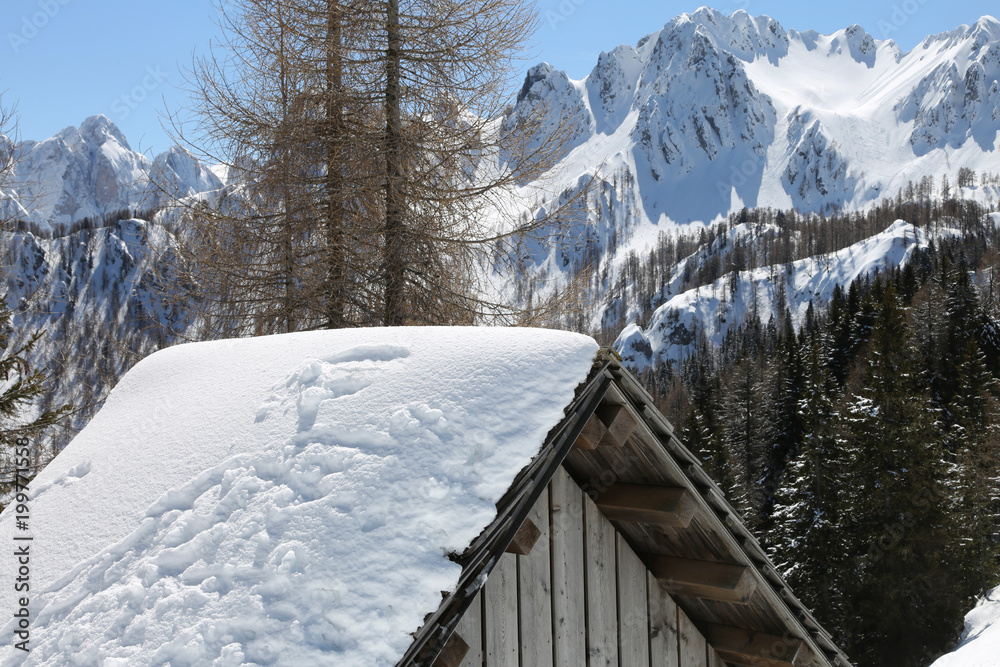 Mountain hut with snowy roof and winter landscape with mountains