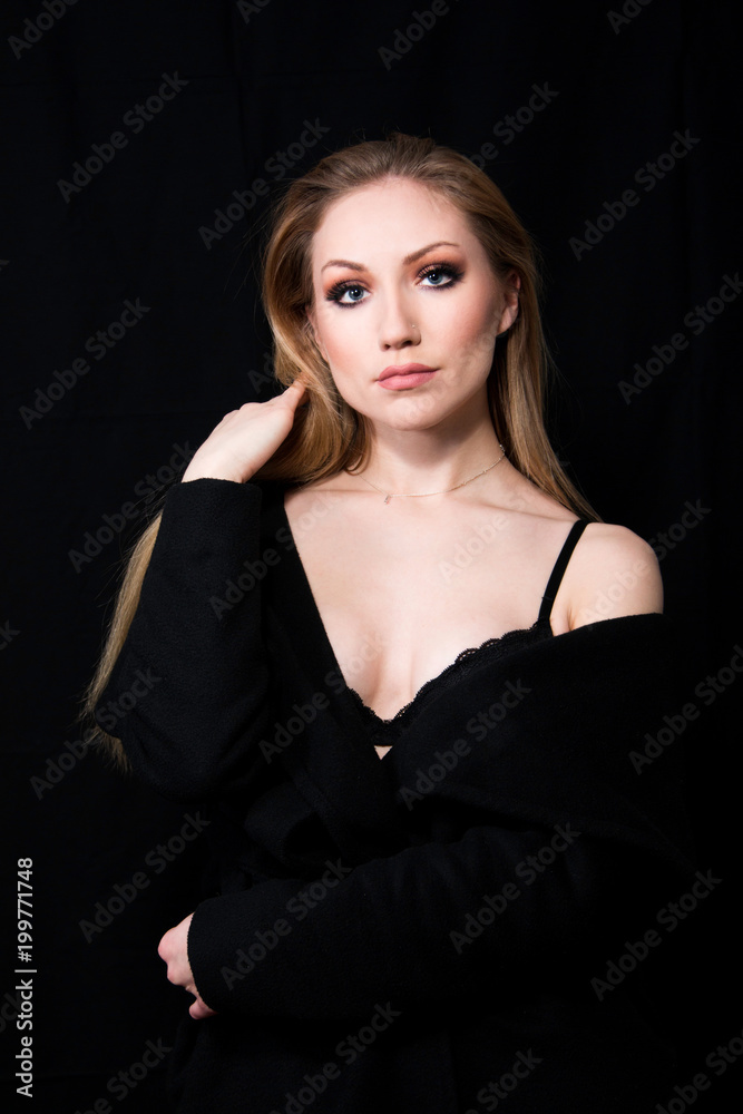 Sexy lady diva with long blonde hair in long coat posing in studio, dark background. Elegant woman. Erotic noir concept. Half body. Sexy lady diva with long blonde hair in long coat posing in studio, dark background. Elegant woman. Erotic noir concept. Half body.