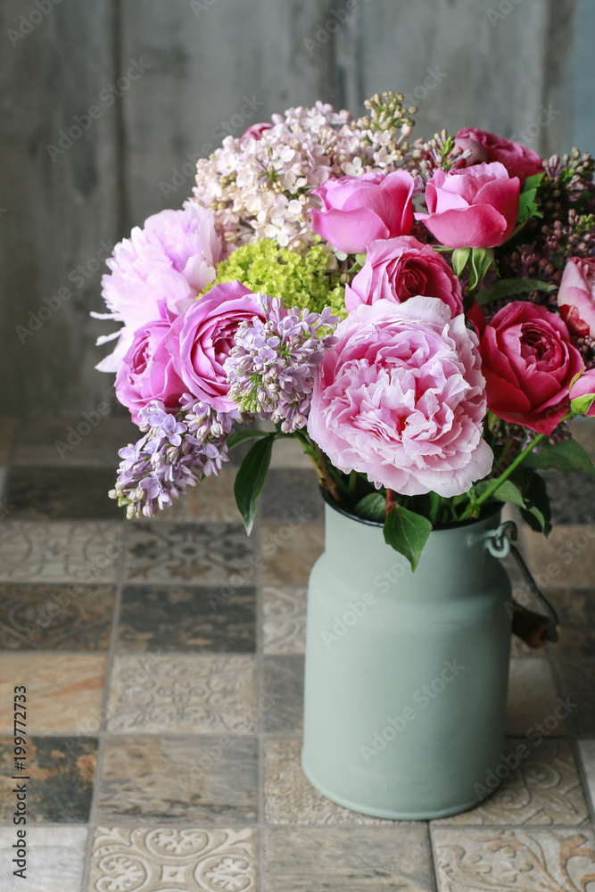 Floral arrangement with pink roses, peonies and lilacs.