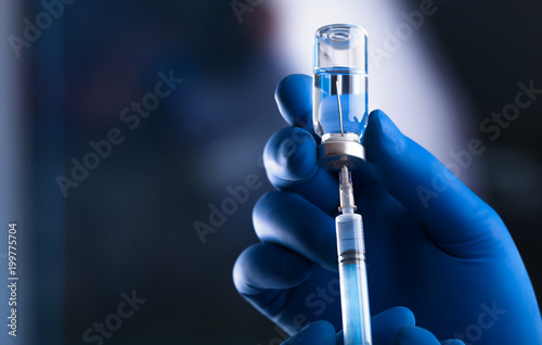 Doctor hand holds syringe and vaccine photo