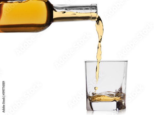 whiskey or cognac poured into a glass from a bottle isolated on a white background