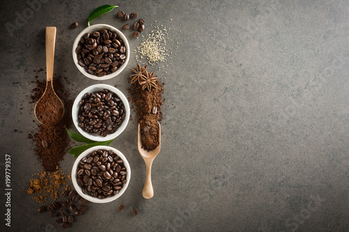 Different varieties of coffee beans with sugar and green leaf on dark vintage background. From top view