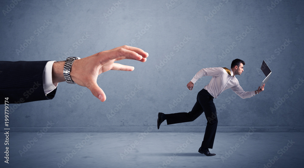 Young miniature businessman running from a big hand with blueish background Young miniature businessman running from a big hand with blueish background