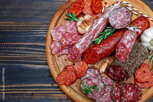 Various types of Dried organic salami sausage on wooden cutting board