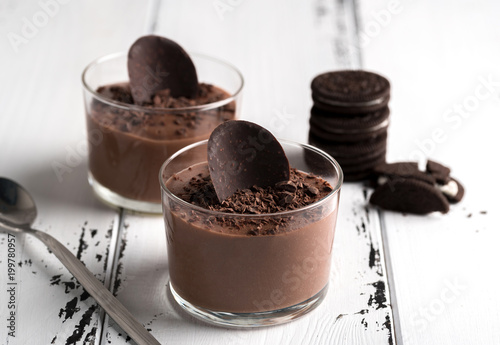 Chocolate mousse in a glasses on a white wood background.