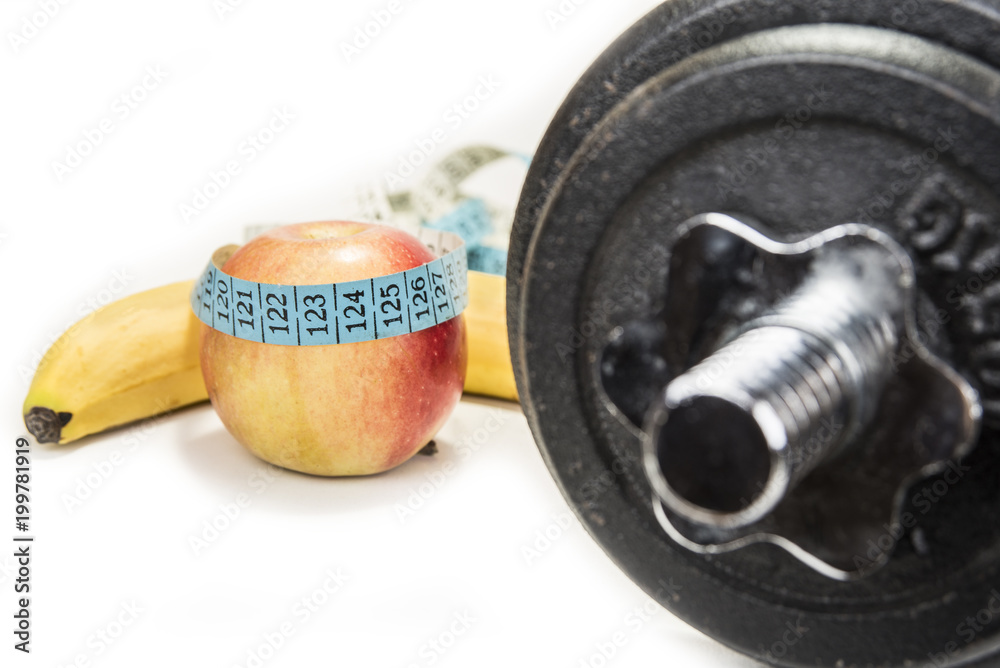 Naklejka premium Dumbbell and an apple with a tape measure, isolated on white