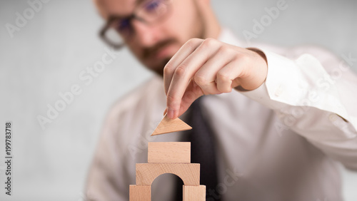 Young handsome businessman using wooden building blocks 