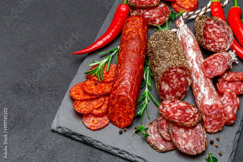 Various types of Dried organic salami sausage on stone serving board