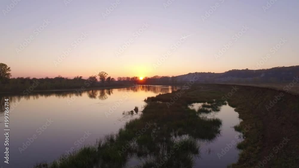 Overgrown broad river sunset sky reflection on water - aerial view