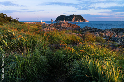 Orange Light with view to Moon Island and Lighthouse during sunset at Seaseom, Seogwipo, Jeju Island, South Korea photo