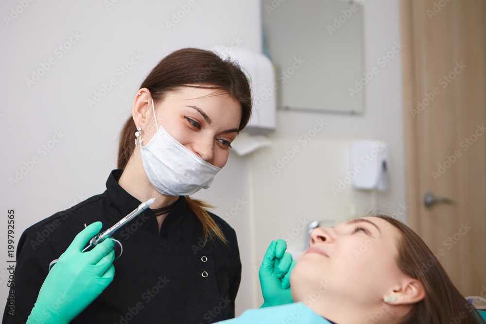 Candid shot of positive professional female dentist wearing mask and