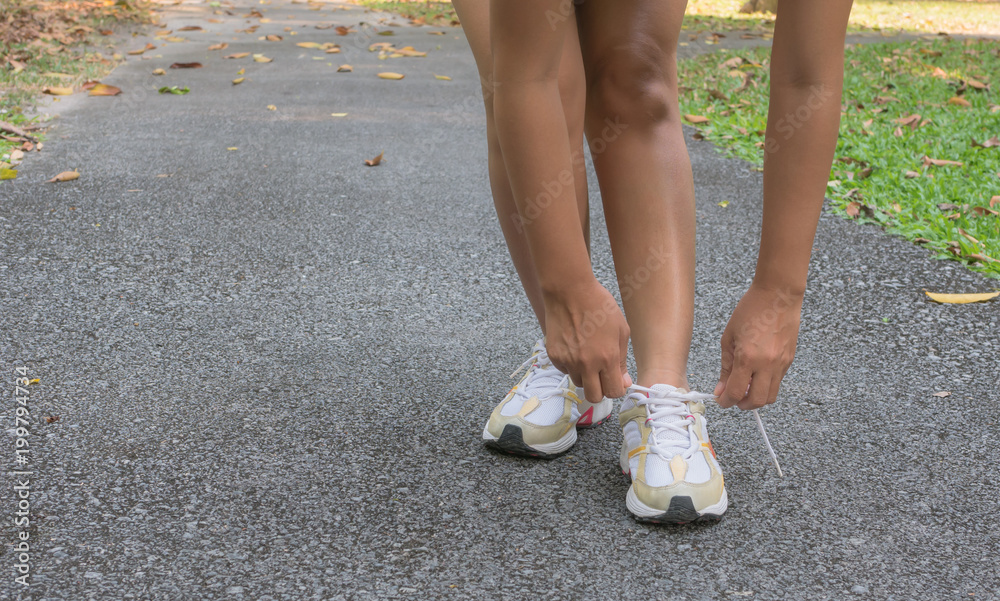 Female athletes are tying shoes, close up sport women, foot and shoes woman on the floor.