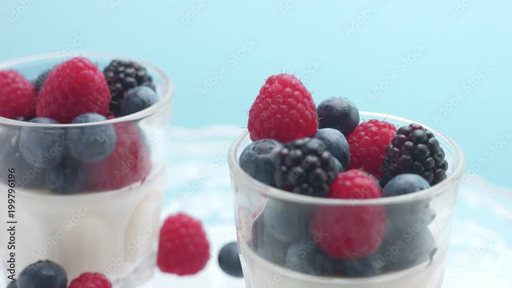 glasses full of yogurt and berries on a crystal plate turning on it's axis in studio minimalist clip