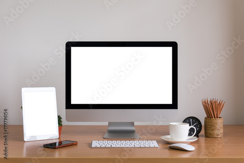 Computer all in one, tablet, smartphone, clock, pencils and coffee cup on wooden table