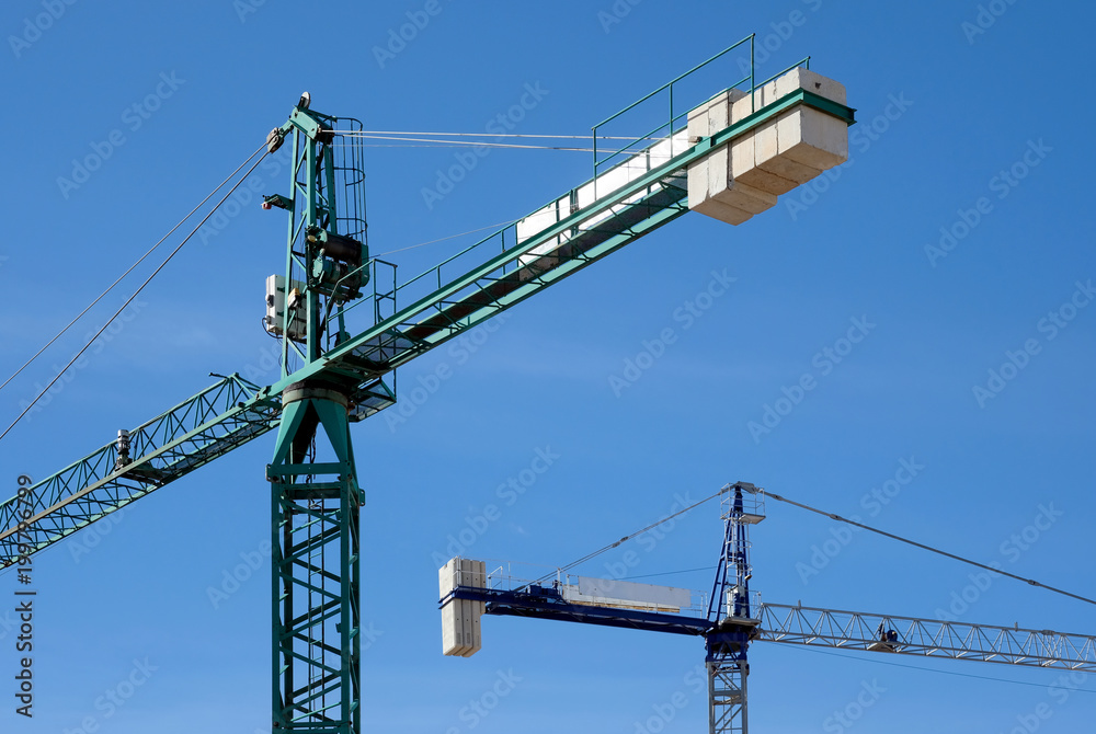 Construction cranes against blue sky