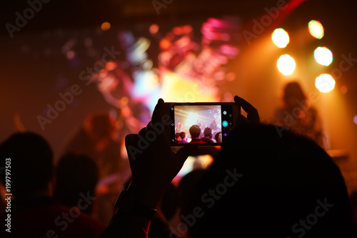 Audience keep taking photo and video at concert with their cellphone focus on the screen with blur background