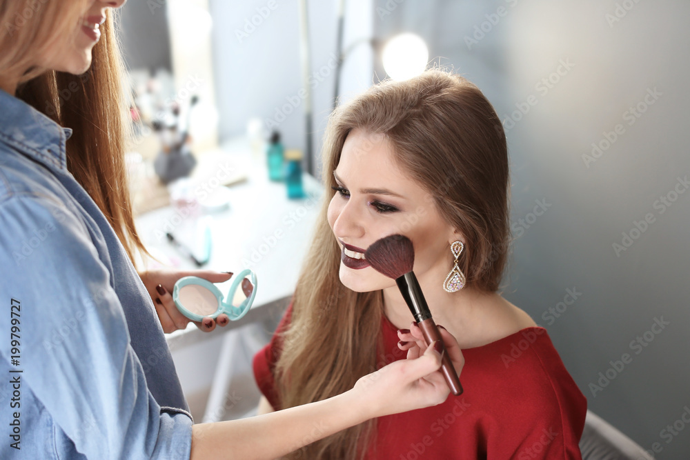 Professional makeup artist working with beautiful young woman in studio Professional makeup artist working with beautiful young woman in studio