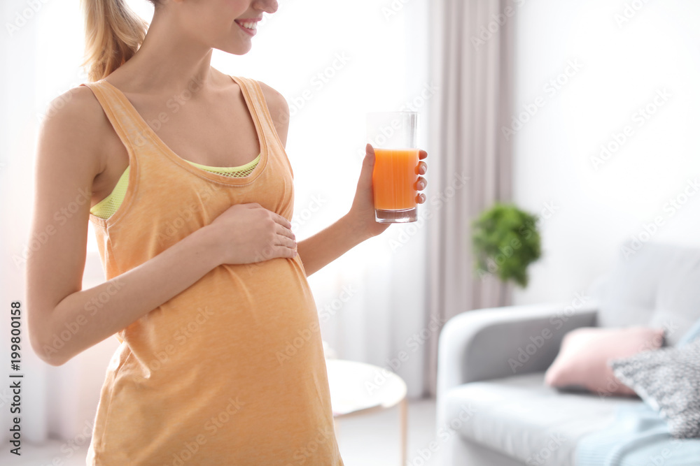 Young pregnant woman holding glass with juice at home Young pregnant woman holding glass with juice at home
