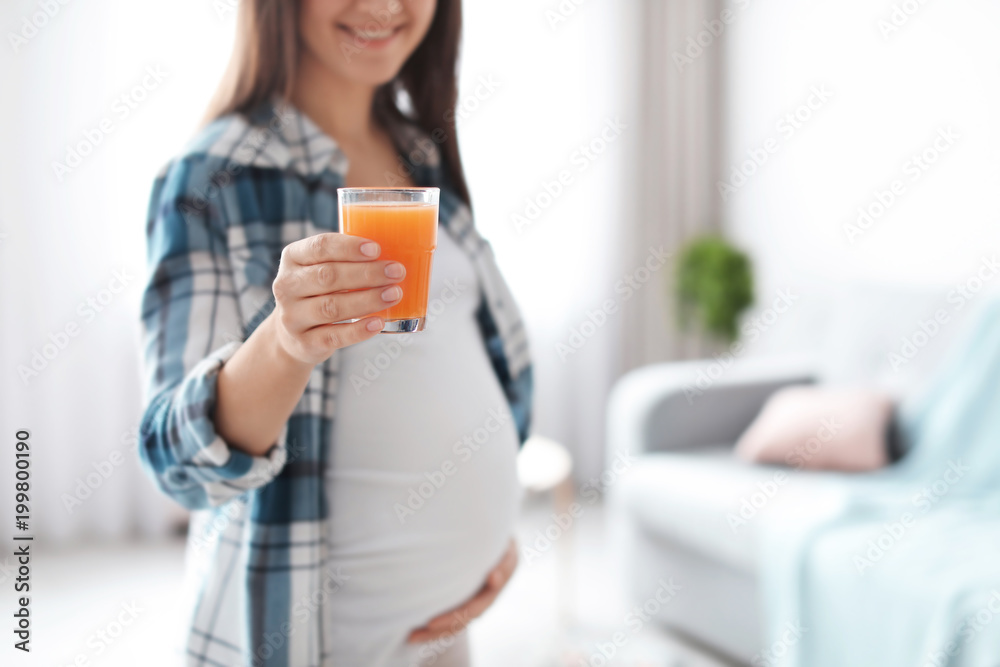 Young pregnant woman holding glass with juice at home Young pregnant woman holding glass with juice at home