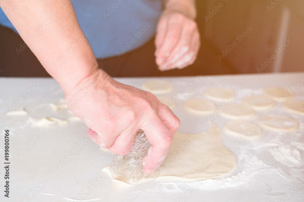 Hands of woman knead the dough on a table, selective focus.