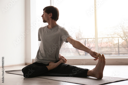 Fototapeta Naklejka Na Ścianę i Meble -  Young man practicing yoga indoors